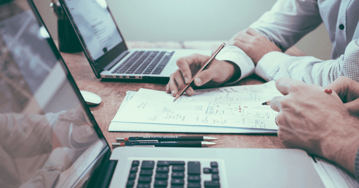 Business professional reviewing documents and laptop checklist before merchant processing application and compliance review