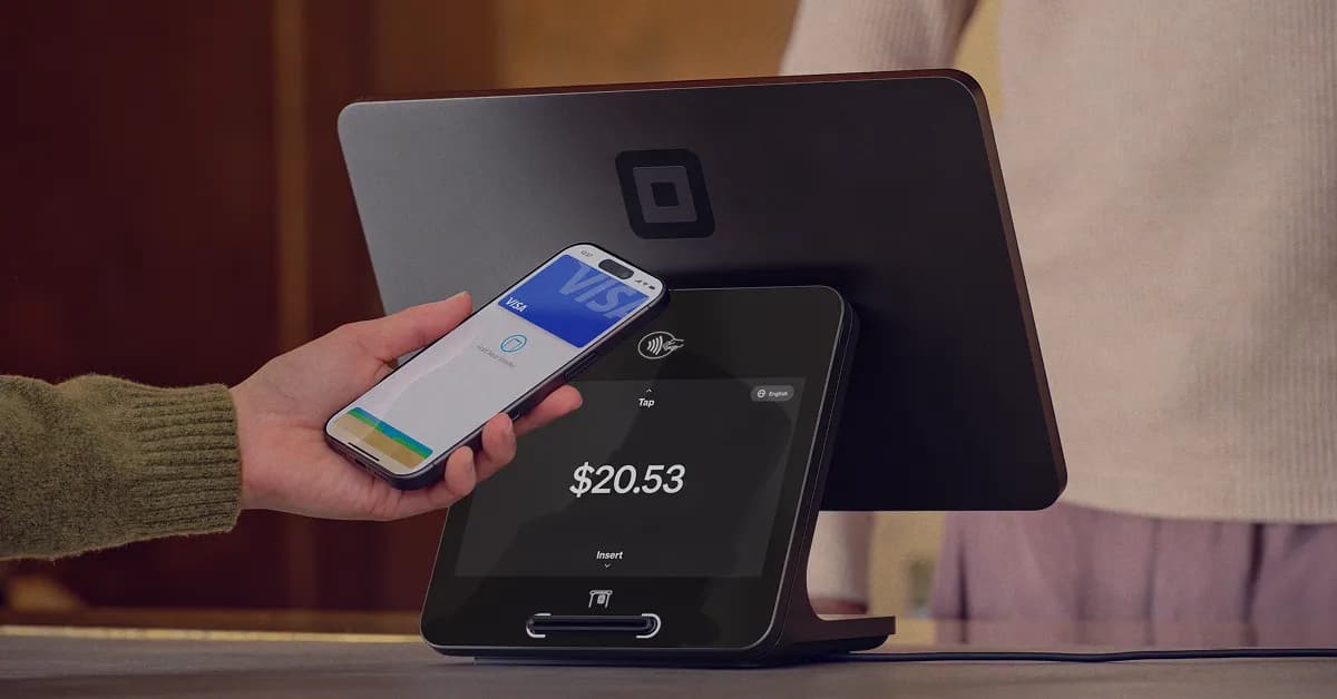 Guest tapping a phone on the Square Register customer screen while the merchant display sits behind it