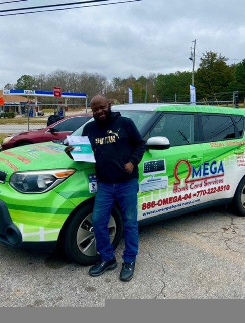 Merchant with Omega Bank Card branded vehicle wrap and rewards materials, Americus, Georgia