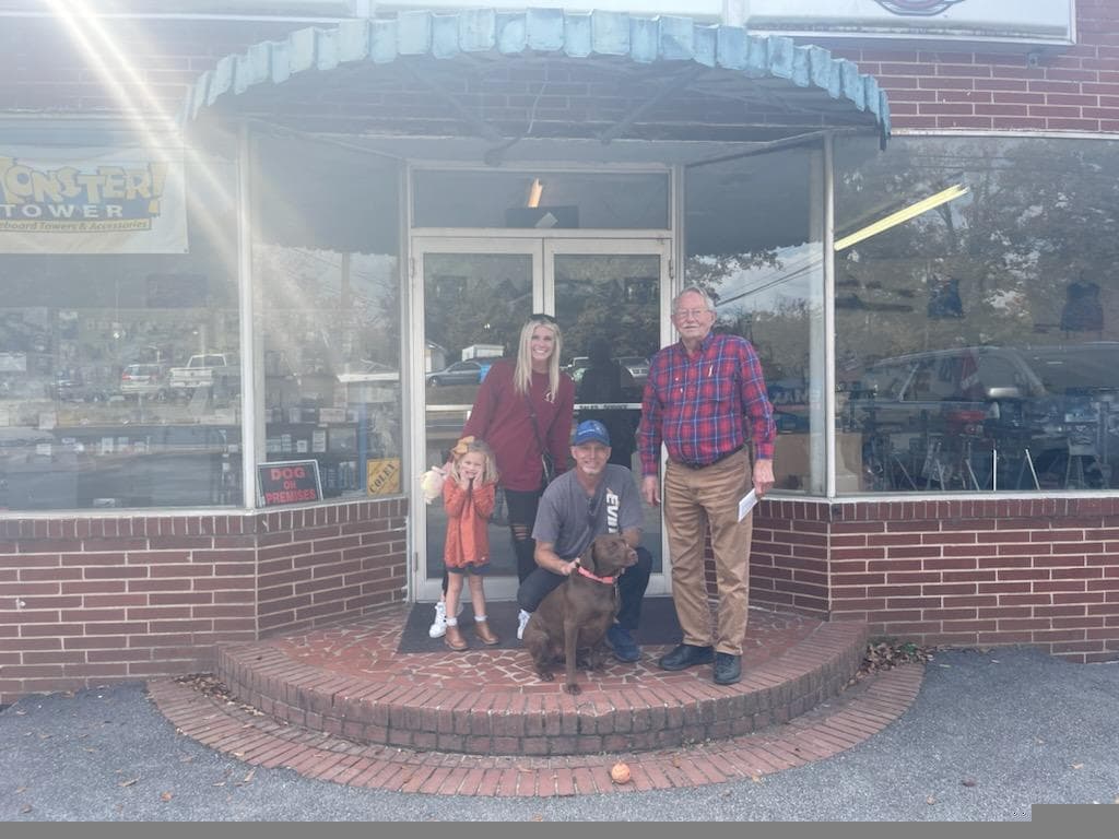 Family and team with dog in front of storefront, Omega rewards merchant partner, Acworth, Georgia