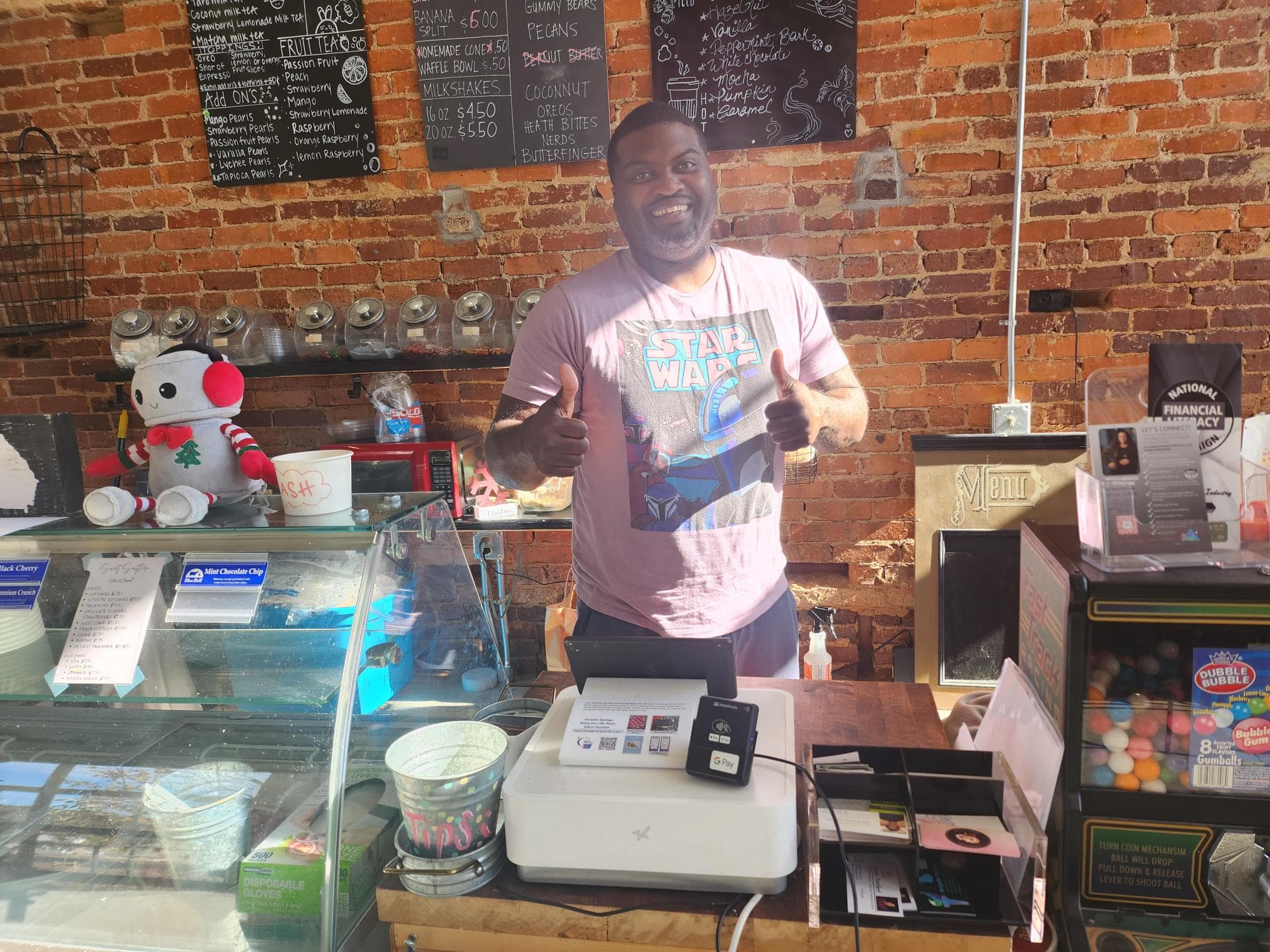 Local merchant behind counter with POS, happy with Omega rewards program, Athens, Georgia