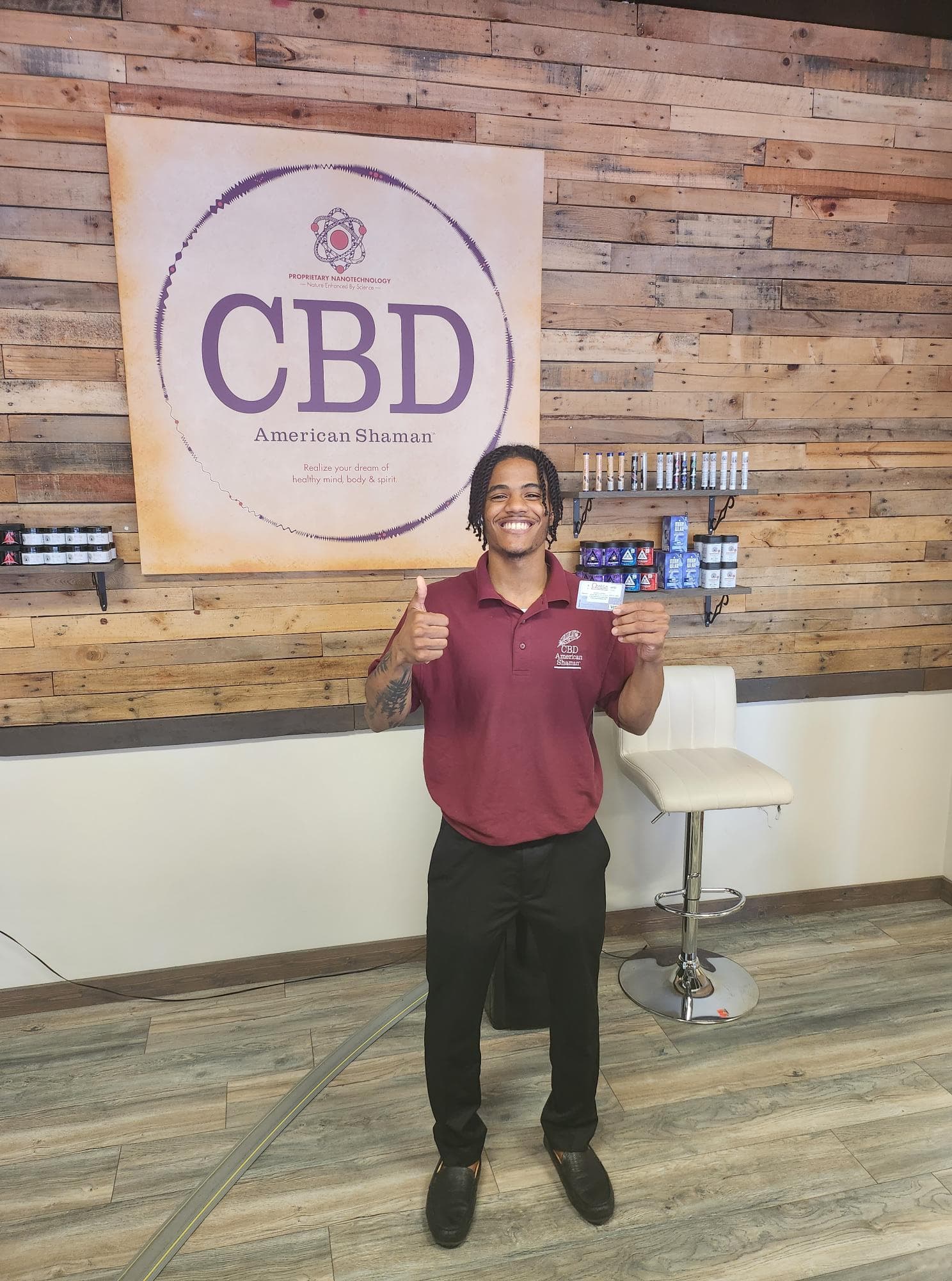 CBD retail merchant giving thumbs up with Omega rewards program card in store